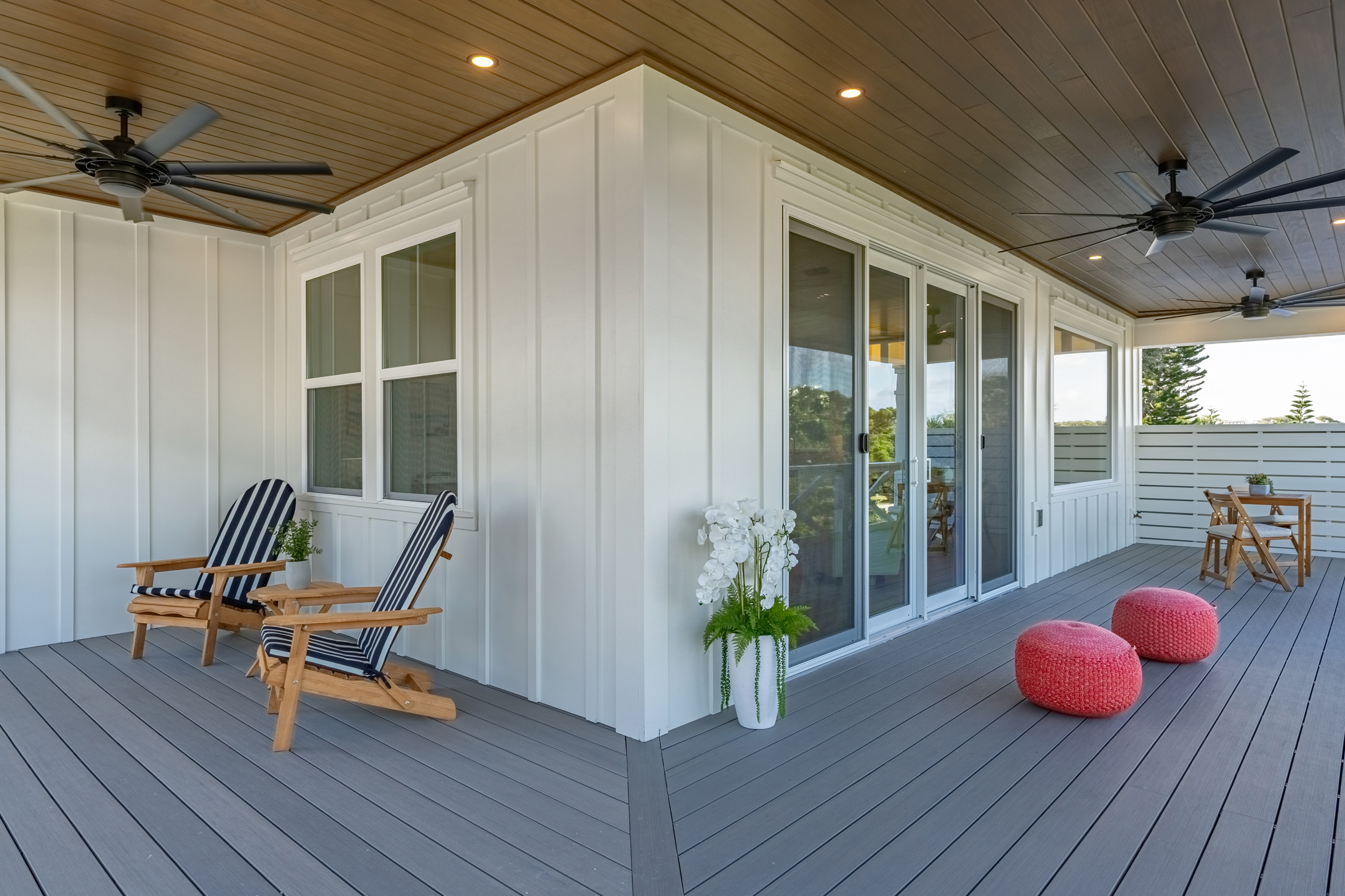 Vacation rental - covered porch with Adirondack chairs, navy stripe cushions, and coral poufs